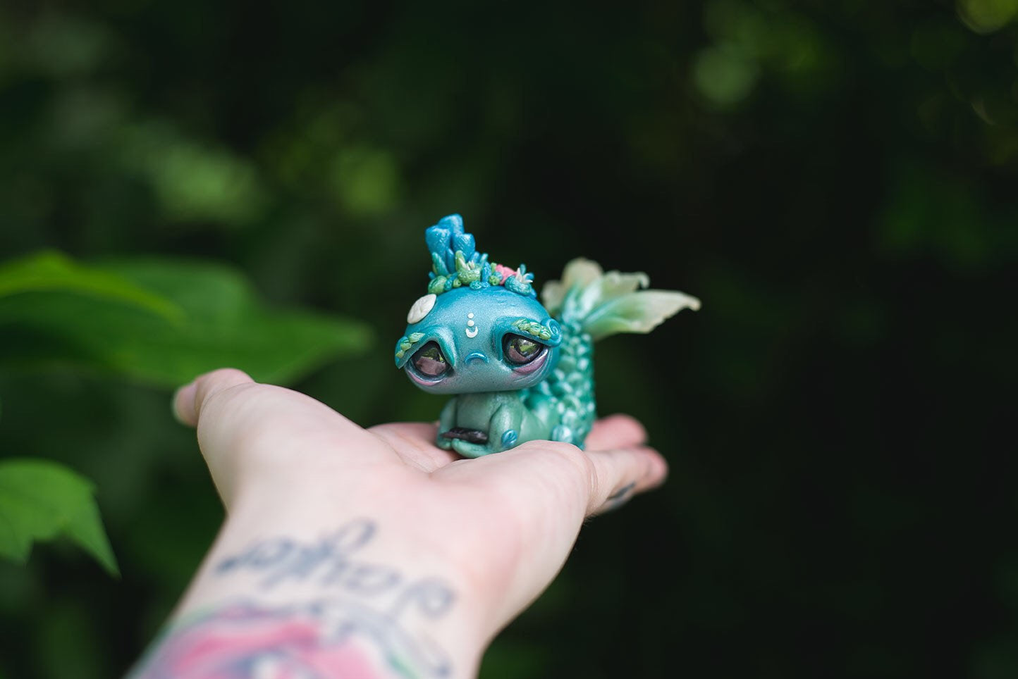 Size Comparison in Hand View of Blue & Green Mermish - handmade polymer clay mermaid creature with coral reef on head holding obsidian