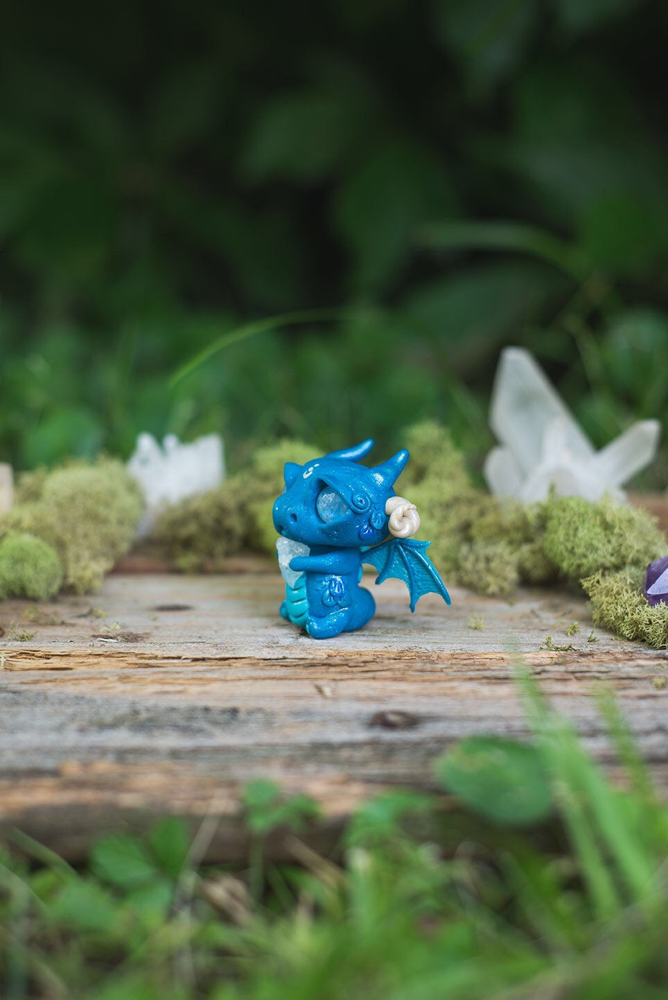 Left-Side View of Blue Dragon Mish - handmade polymer clay dragon creature with tail and wings, holding aquamarine crystal